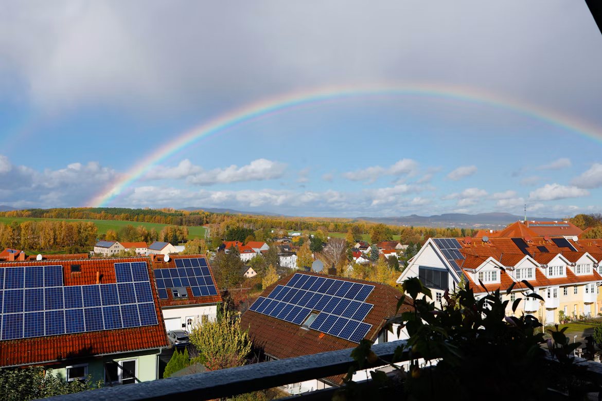 Boligområde med solcellepaneler og regnbue